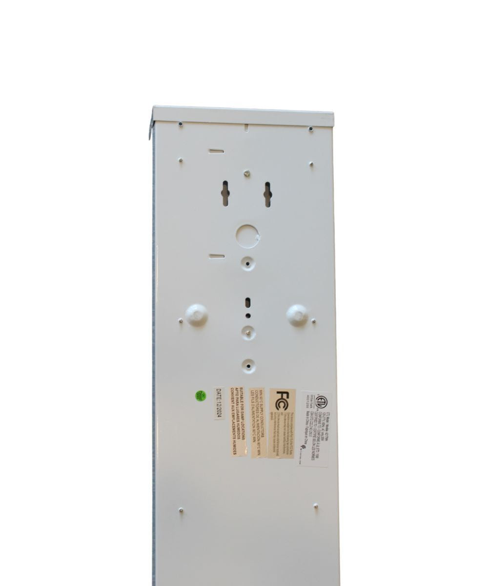Back view of a white integrated LED light fixture with mounting holes and safety label.
