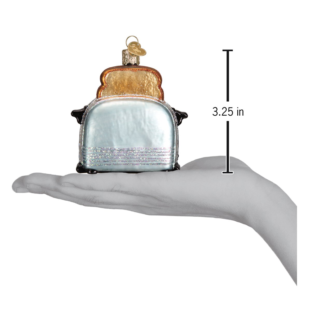 Decorative glass ornament of a toaster with bread on top, shown with a hand for scale.
