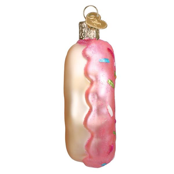 Glass ornament shaped like a pink donut with white cream on a white background