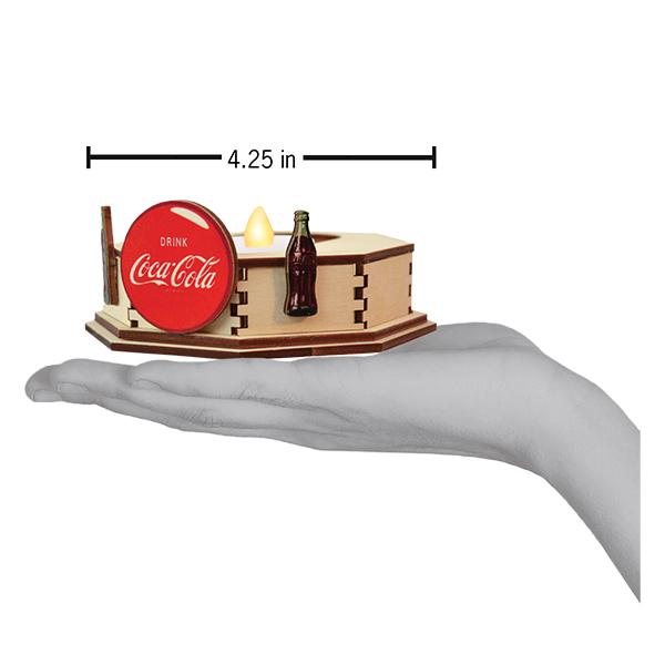 Miniature Coca-Cola display with a bottle and sign held in a hand, showing size measurement.