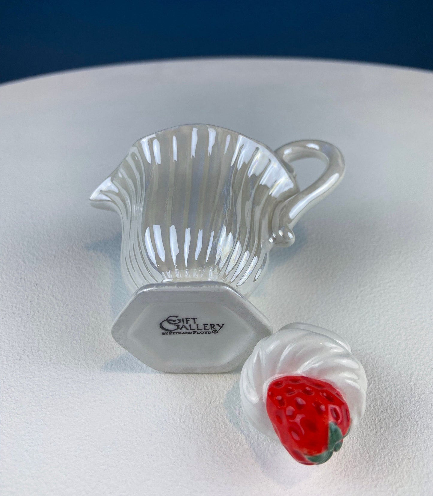 Clear glass strawberry-shaped object with a red center on a white surface.
