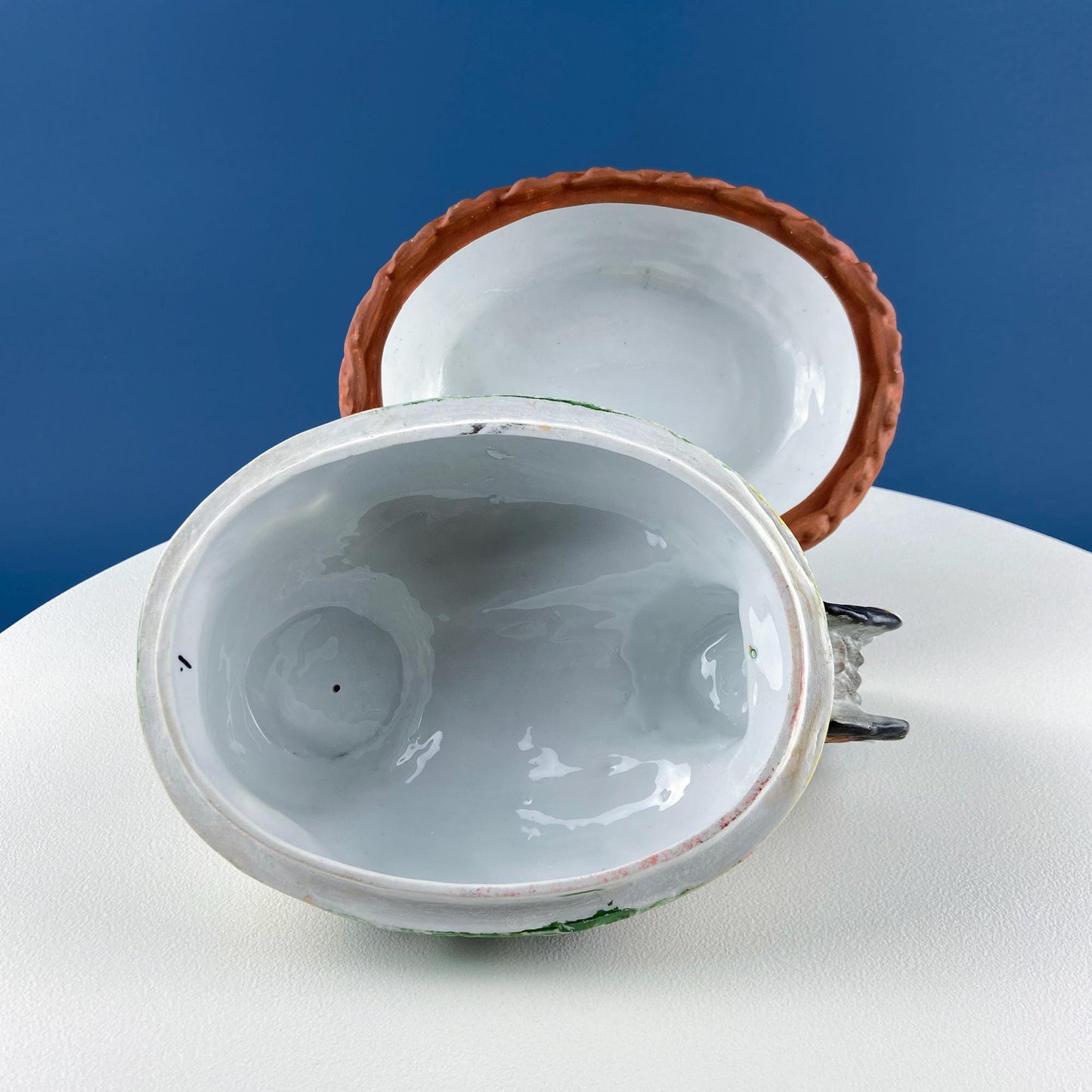 Close-up of a ceramic teapot with a lid on a white surface against a blue background
