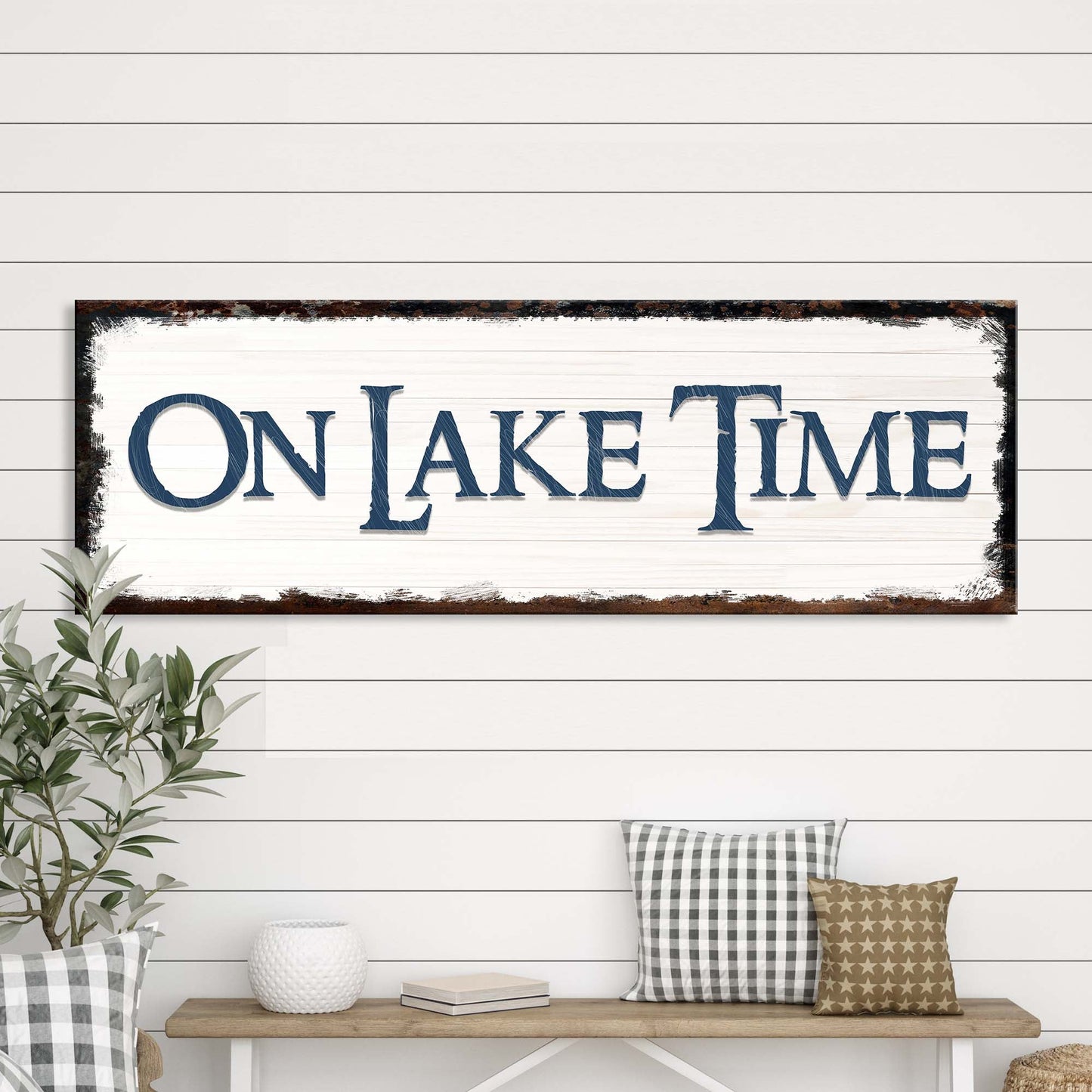 Decorative sign with 'ON LAKE TIME' text on a wall above a bench with pillows.