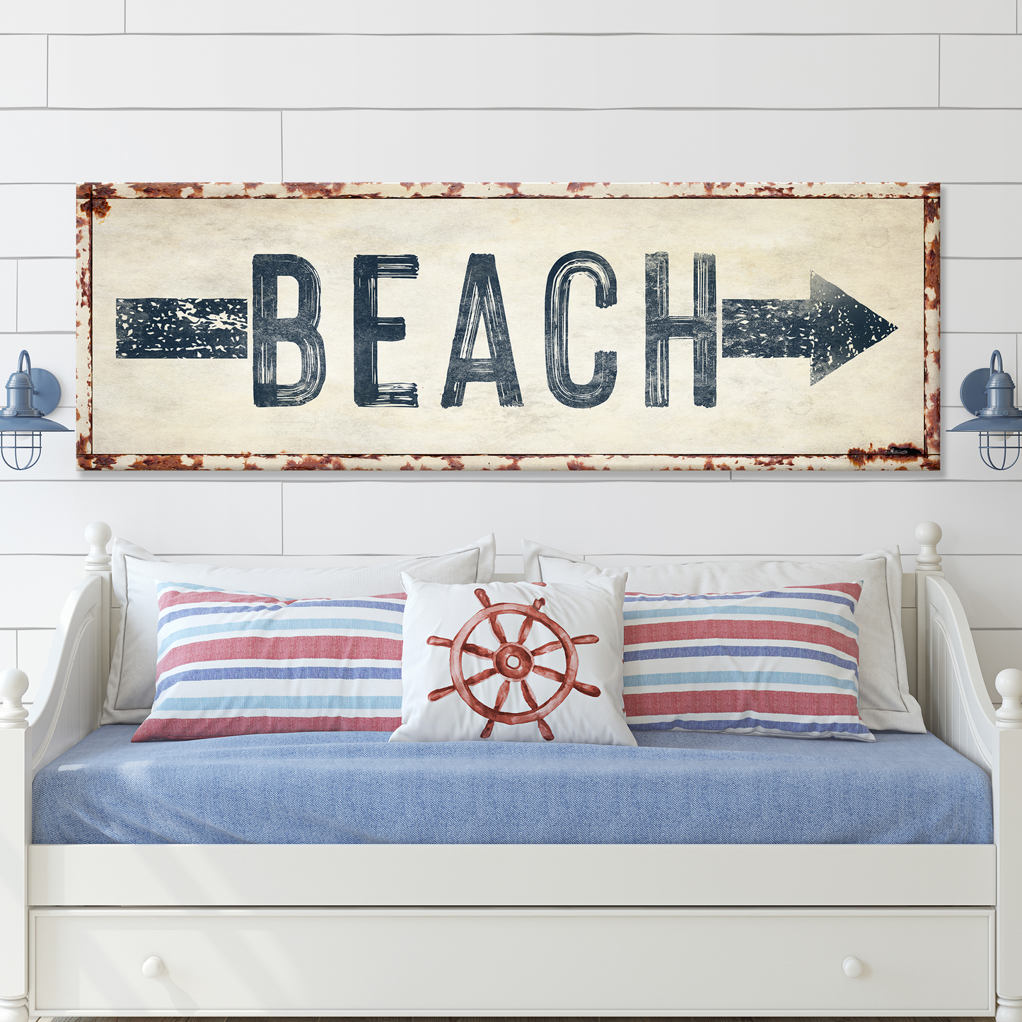 Decorative sign with 'BEACH' text above a bed with nautical-themed pillows.