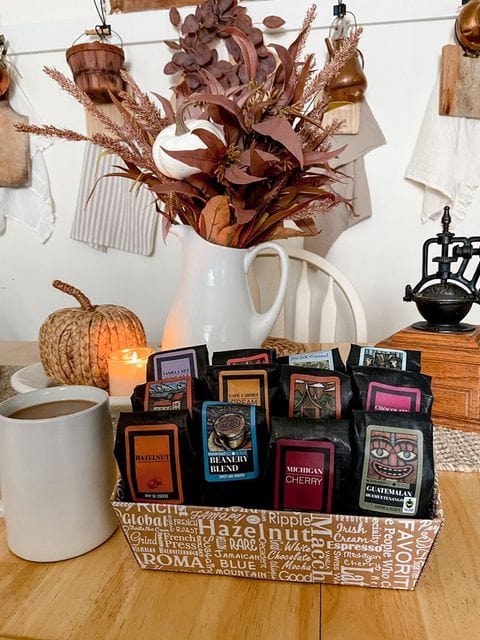 Indulgent Selection Gift Box featuring gourmet coffee samplers and a cozy autumn setup with a coffee mug.