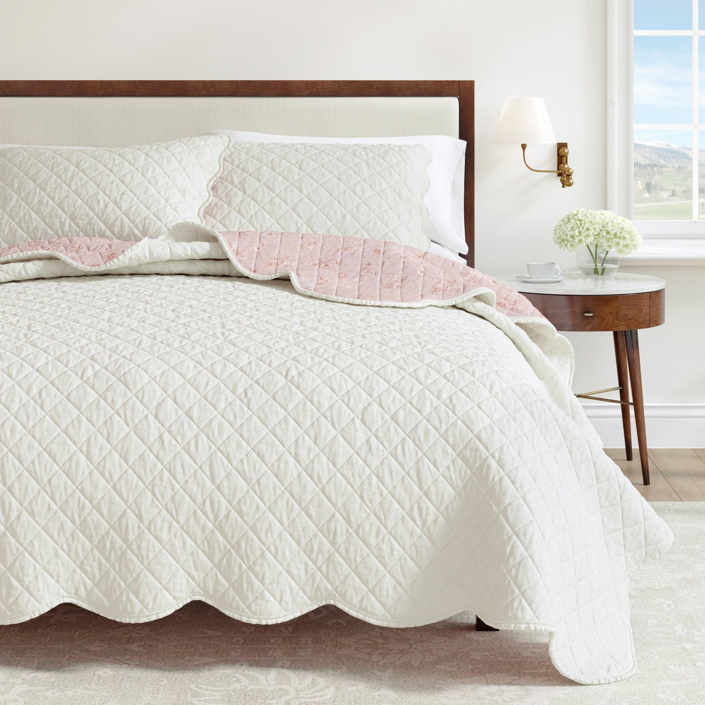 Quilted bedspread with pink trim on a bed in a bedroom setting.