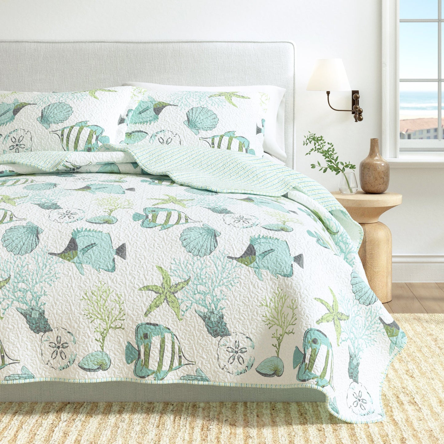 Bed with a sea-themed comforter featuring fish, shells, and starfish in a bedroom setting.