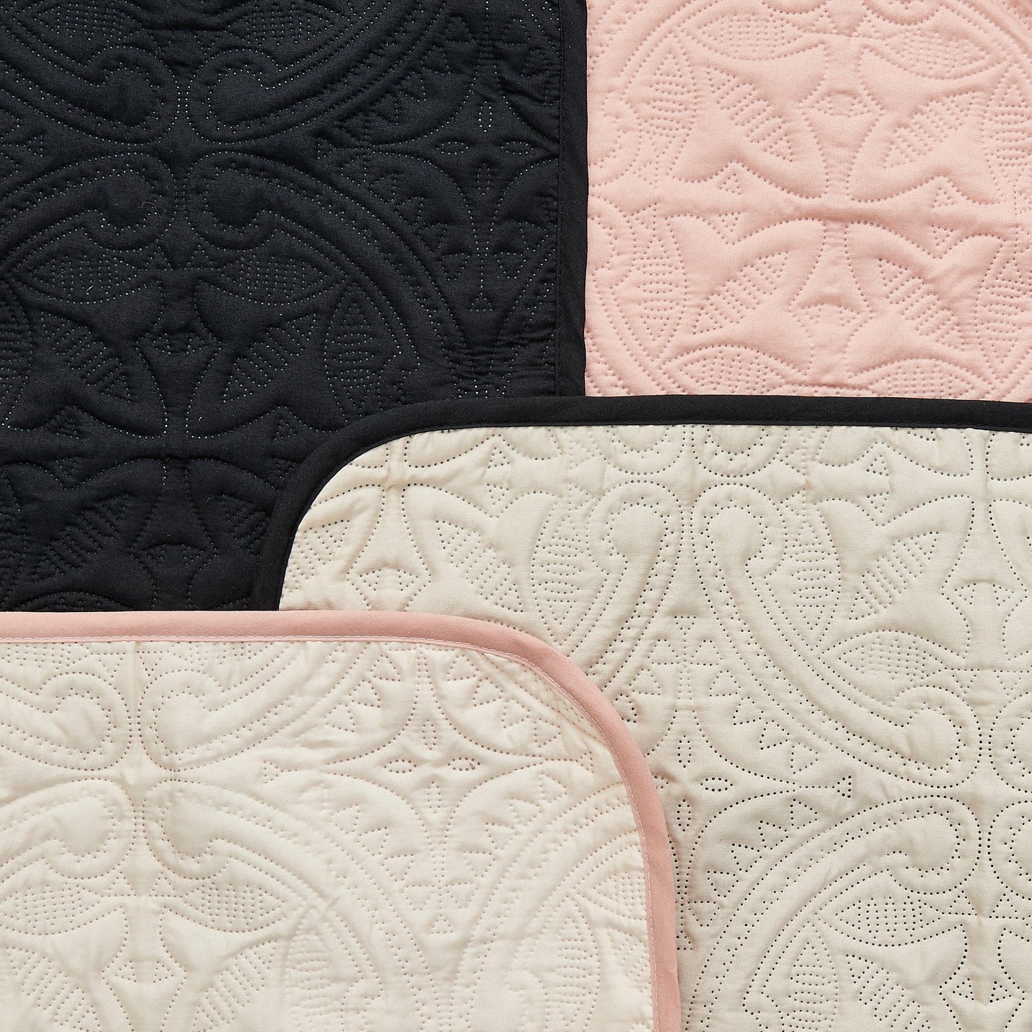 Quilted fabric with black, pink, and beige patterns.