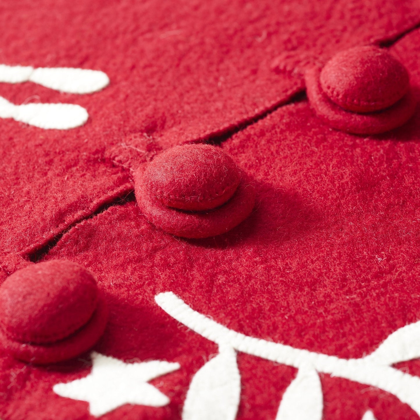 Close-up of handmade felt buttons on the Handmade Felt Branches and Stars Red Christmas Tree Skirt 60.
