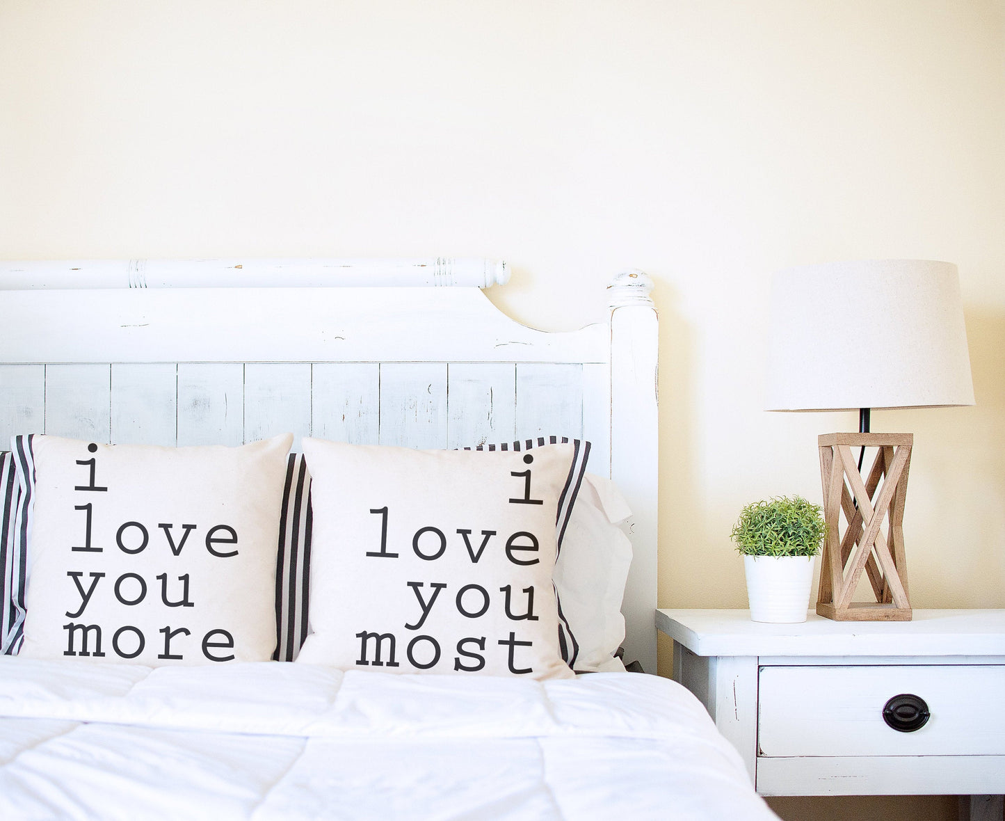 I Love You More Pillow Cover 18x18 inch on a bed with a decorative lamp and nightstand.