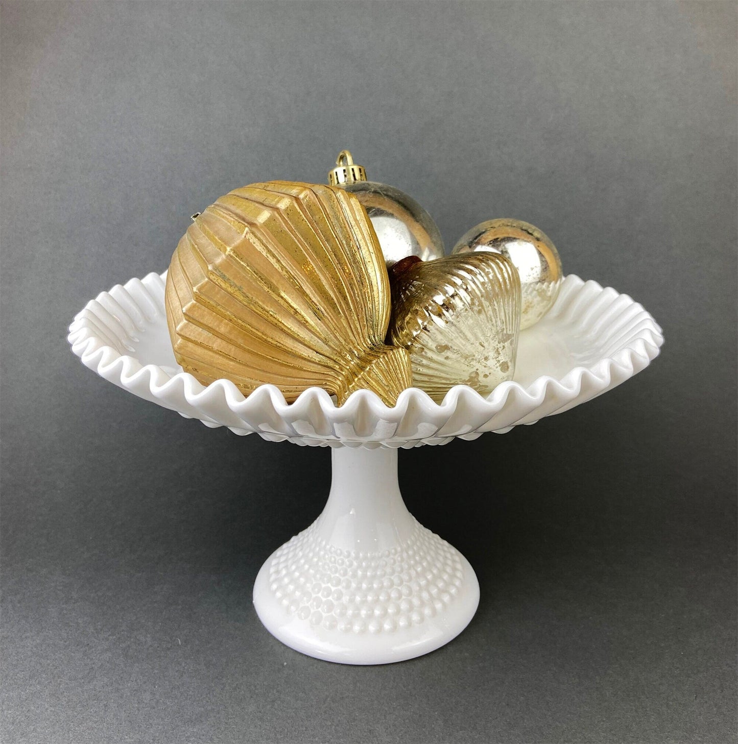 Decorative glass ornaments on a white pedestal against a gray background