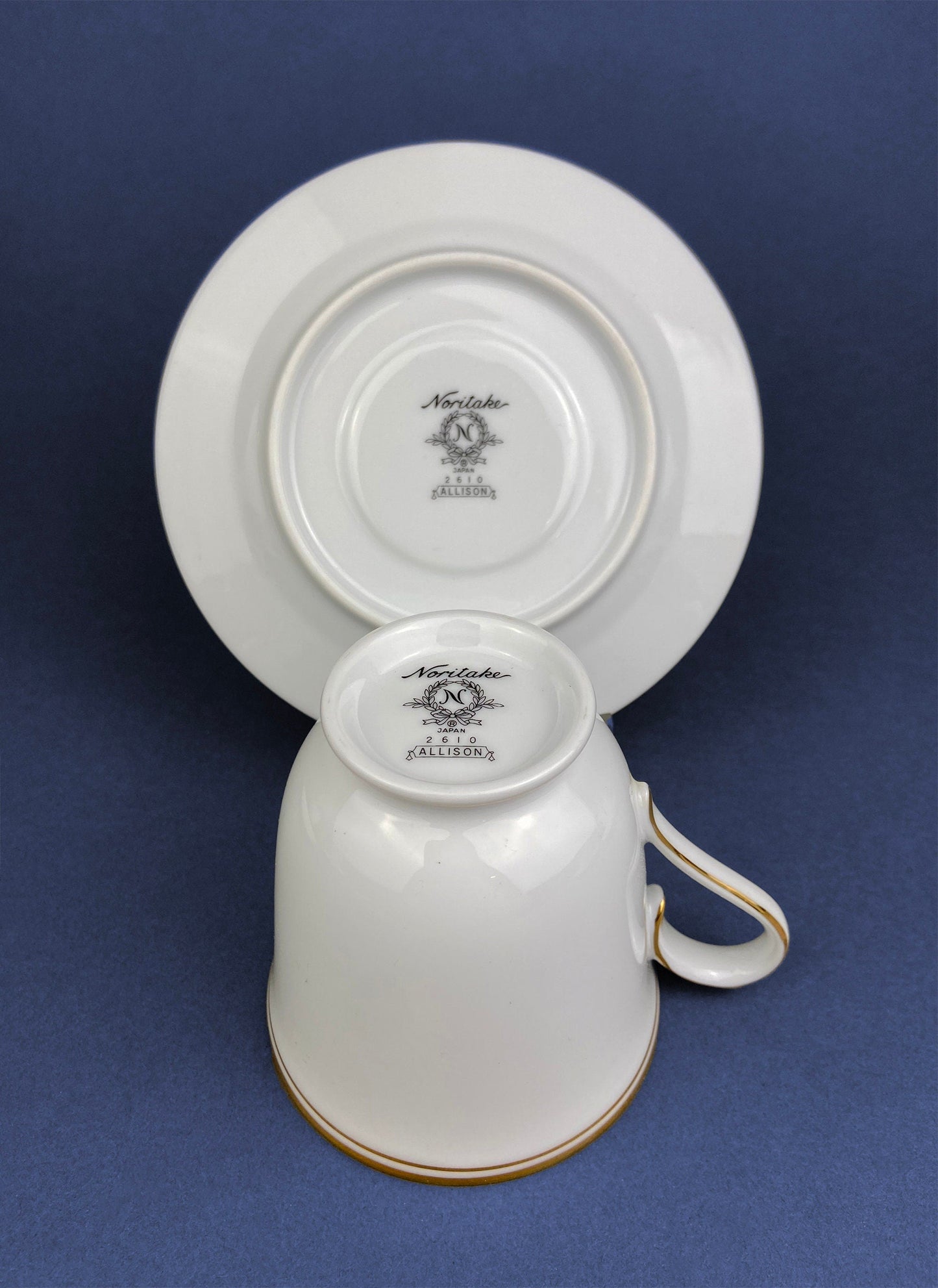 White ceramic cup and saucer with 'Noritake' branding on a blue background