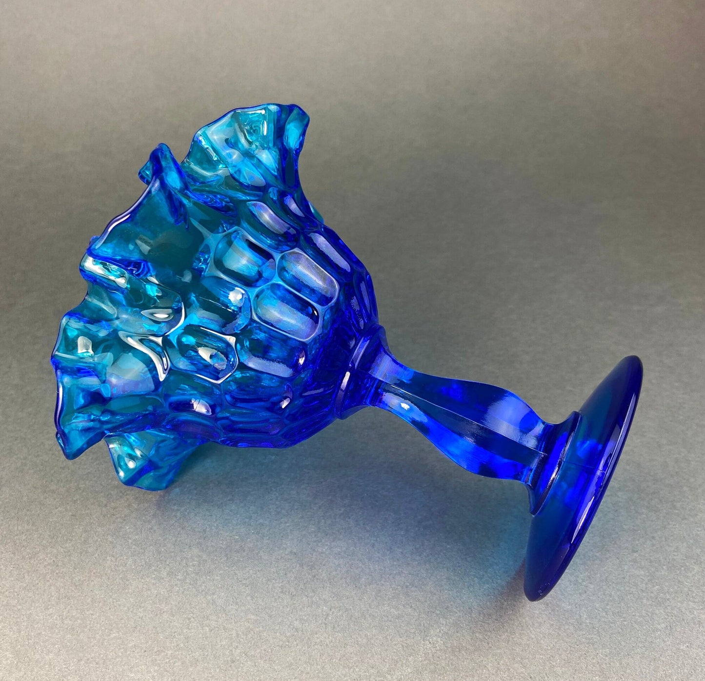 Blue glass footed bowl on a gray background