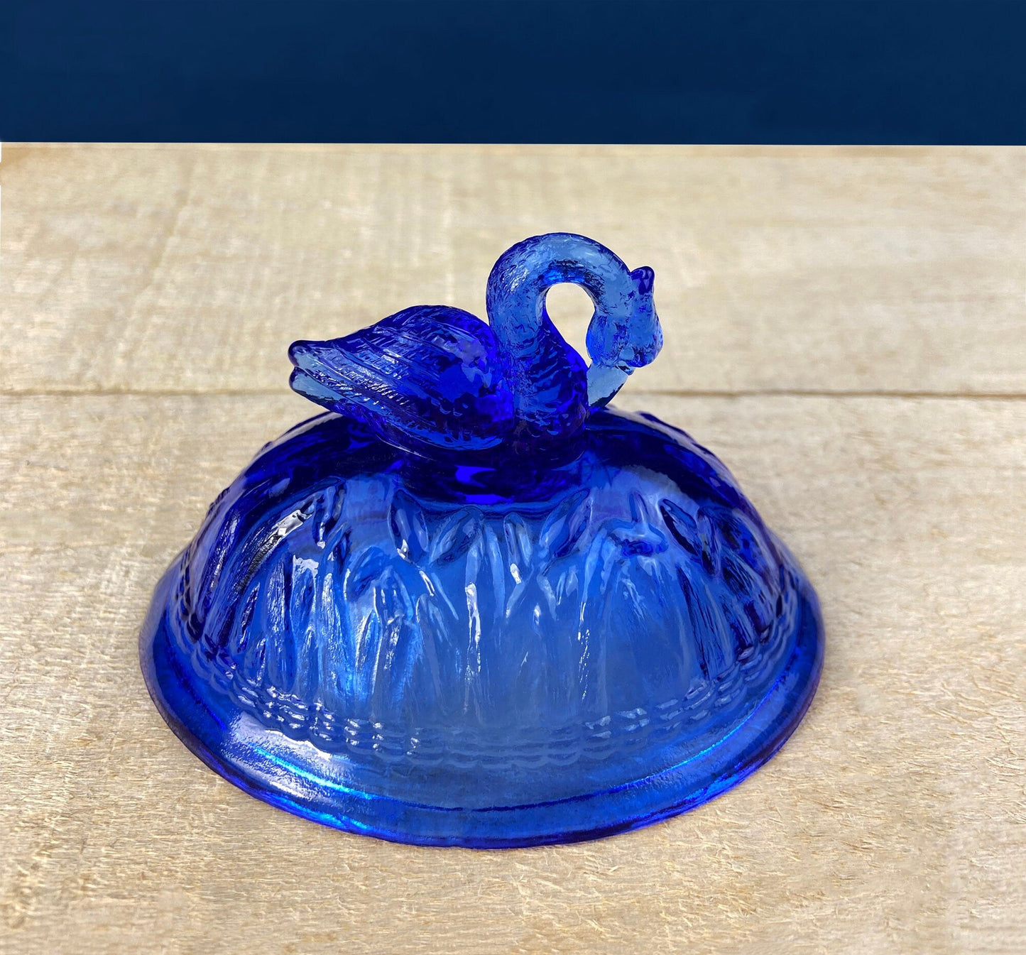 Blue glass dome with a swan on top on a wooden surface