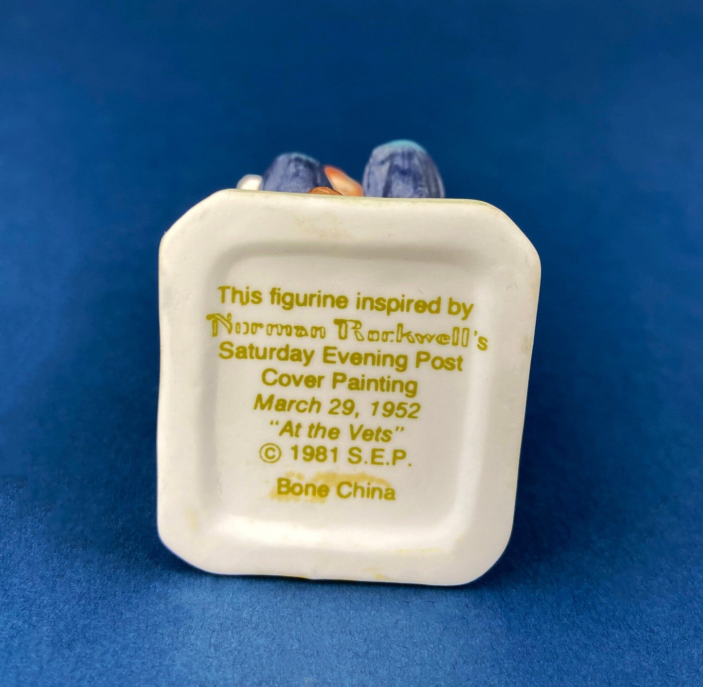 Back of a figurine with text "inspired by Norman Rockwell's Saturday Evening Post" on a blue background