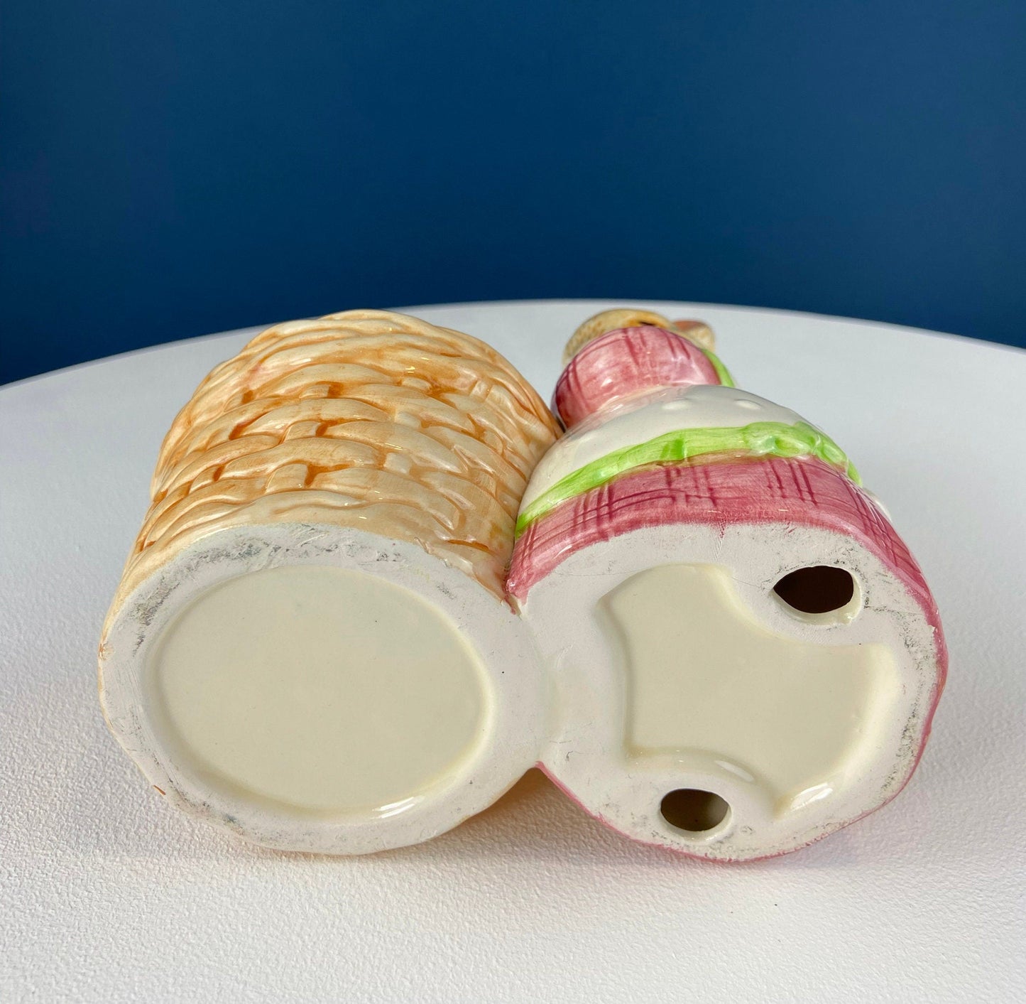 Ceramic bunny with basket on a white surface with a blue background