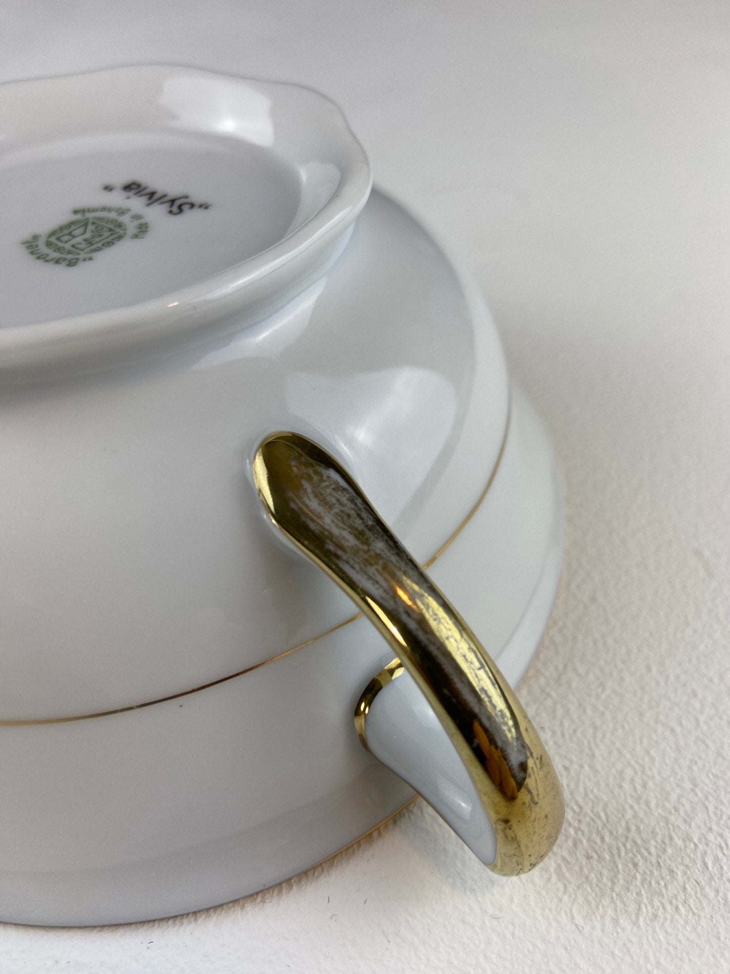 White ceramic dish with a gold handle on a white background