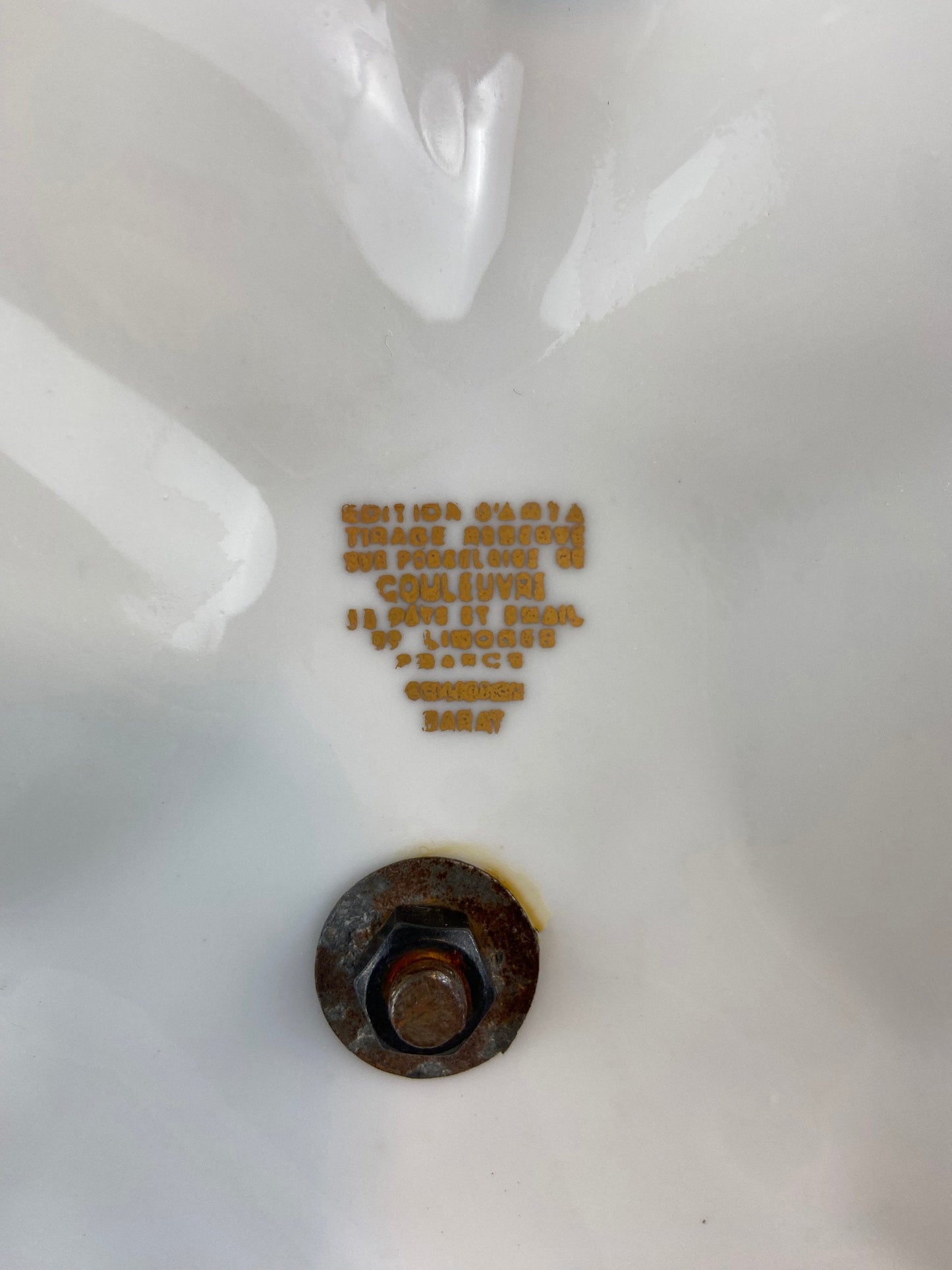 Close-up of a white container with a rusty cap and text in gold.