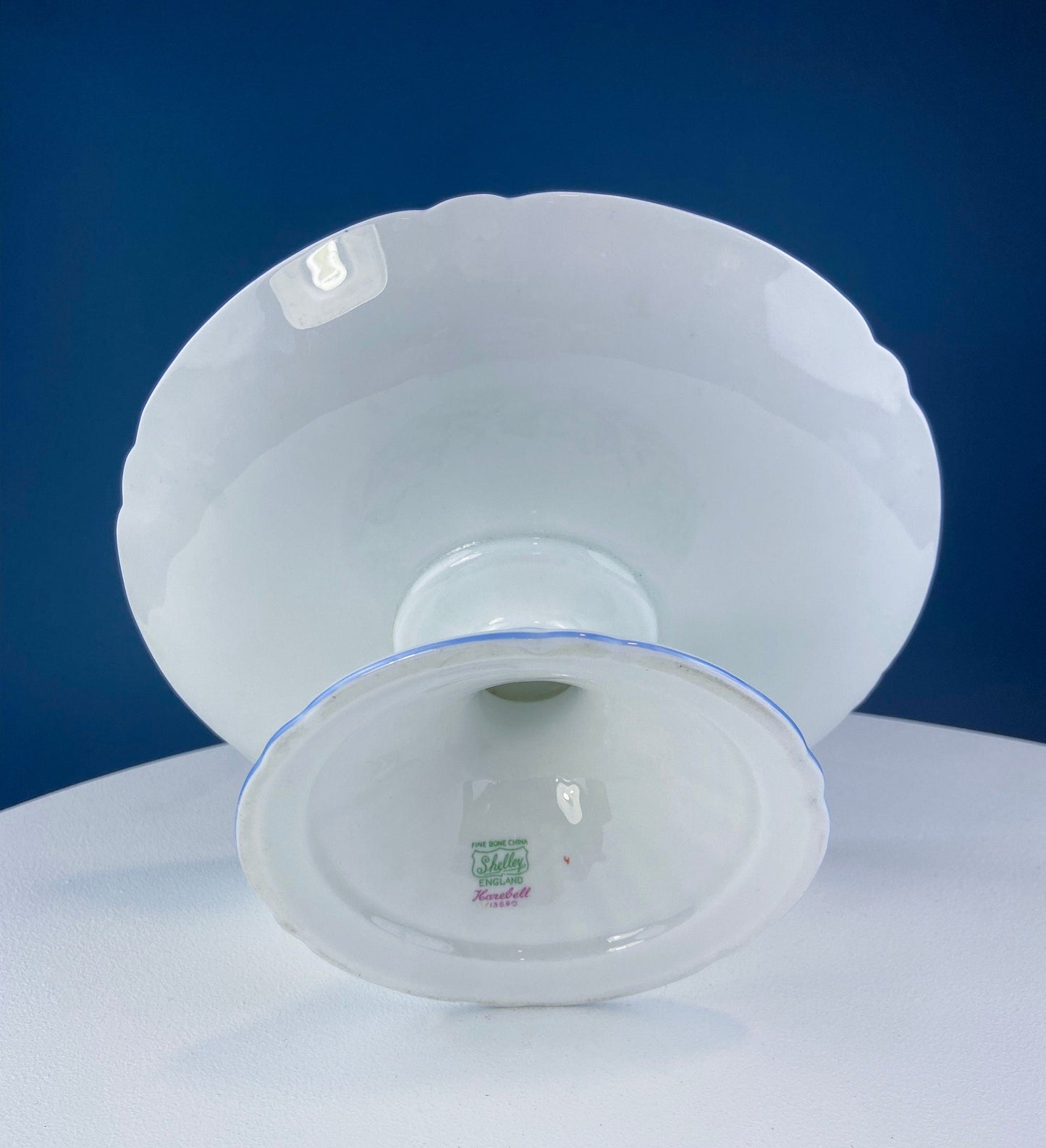 White ceramic bowl with scalloped edge on a blue background