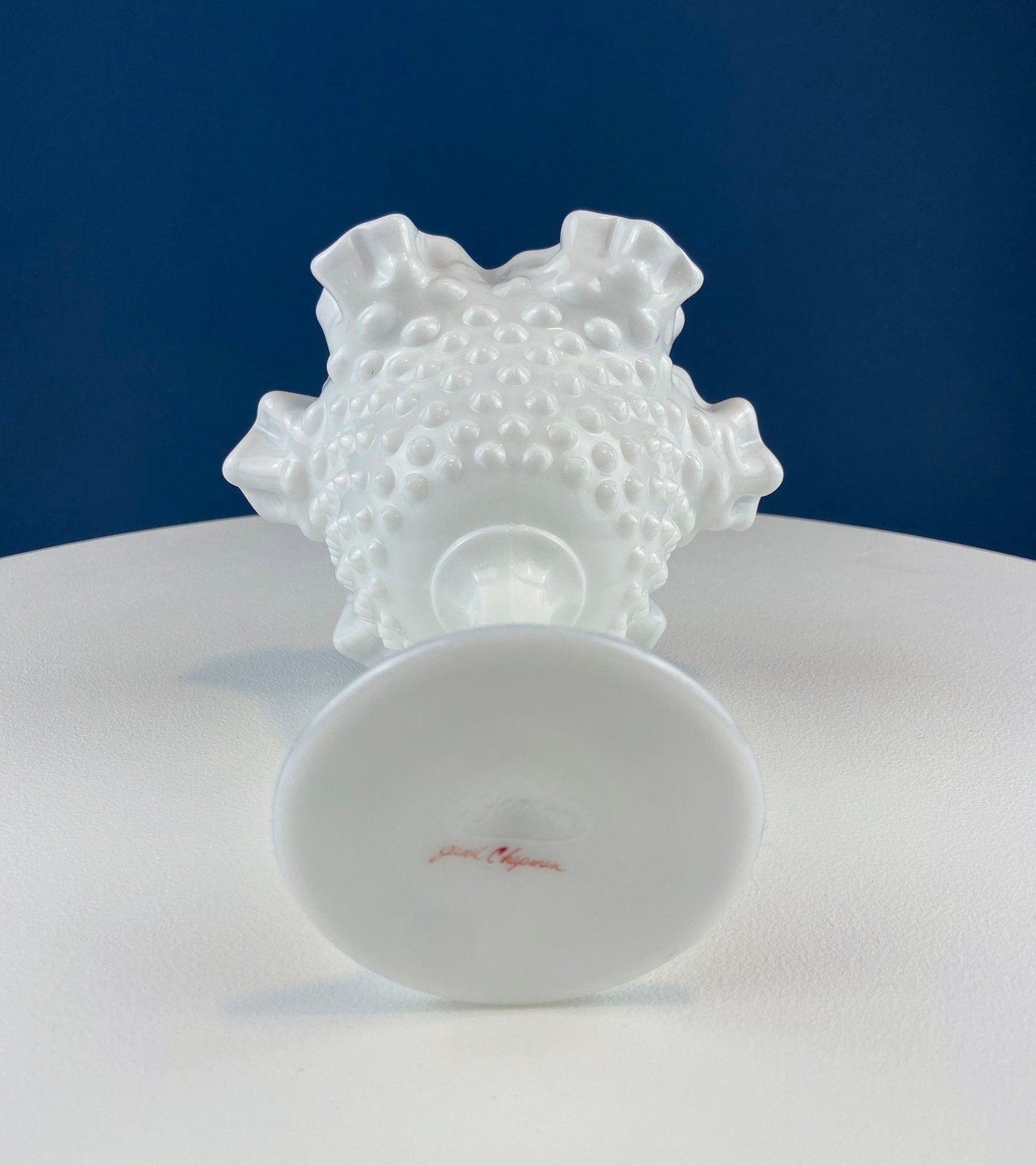White ceramic dish with textured top and smooth base on a white surface with blue background