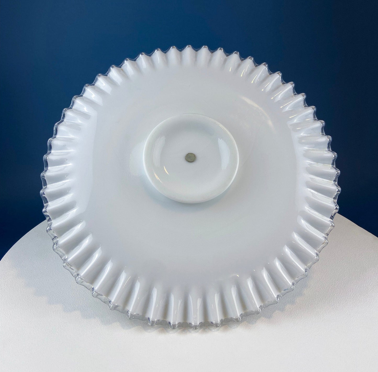 White serving stand with ribbed rim on a blue background