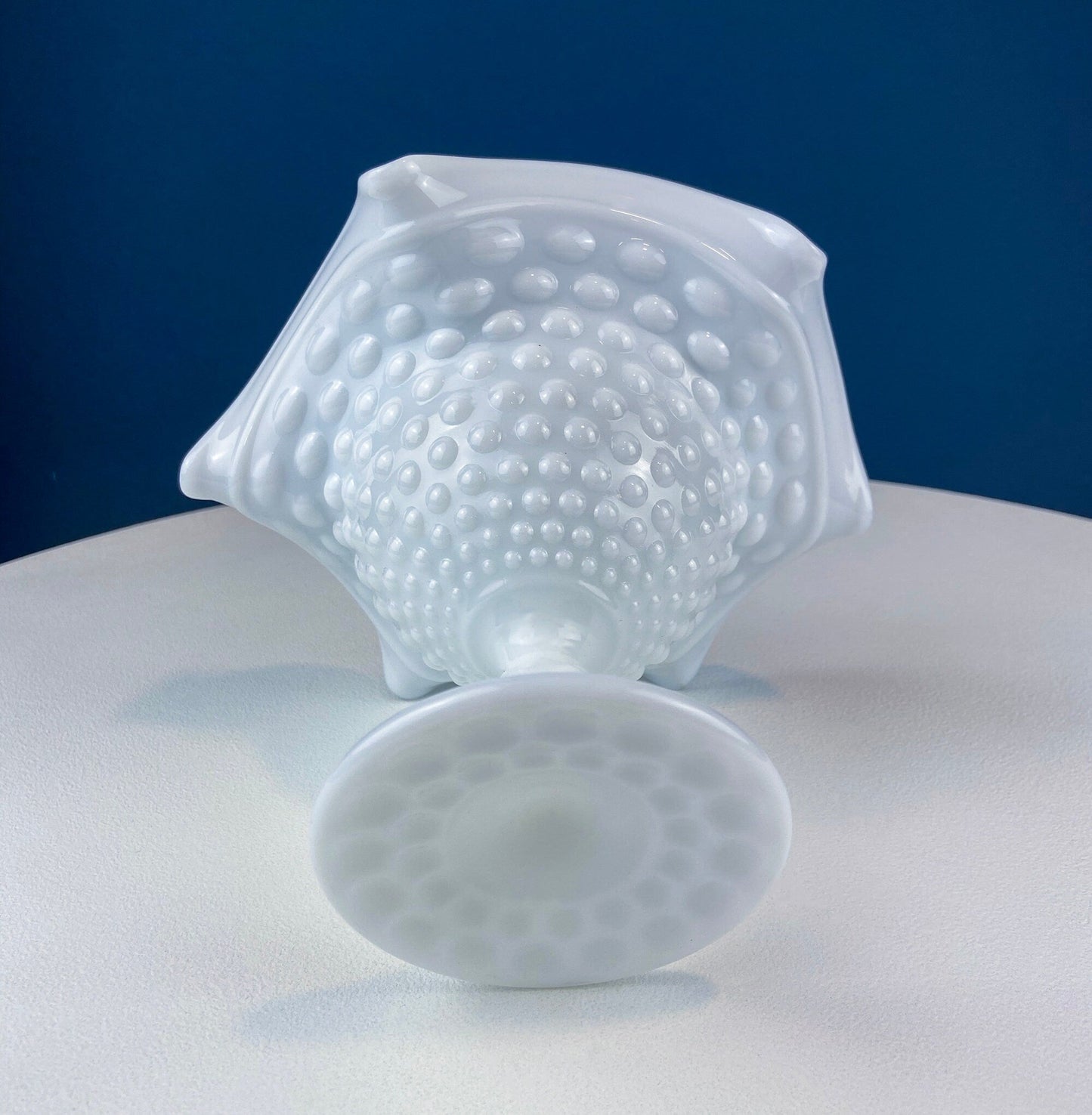White textured glass bowl on a white surface with a blue background