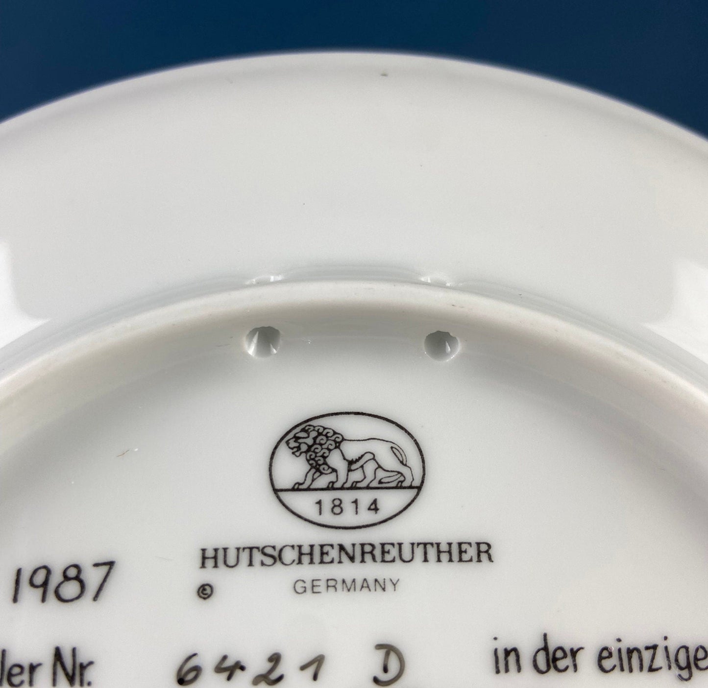 Hutschenreuther brand logo on a white dish with blue background