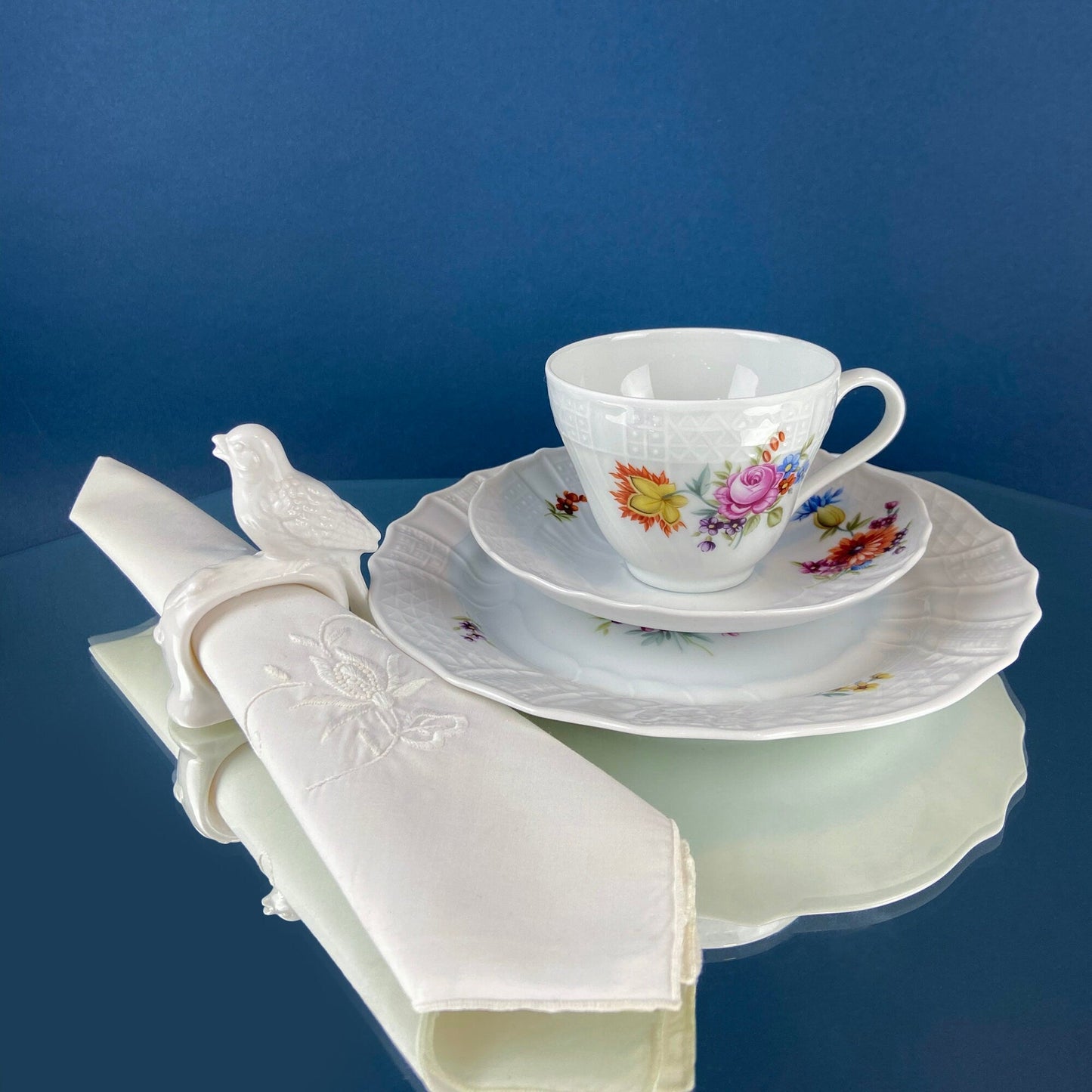 Vintage-style teacup and saucer with floral design on a blue background