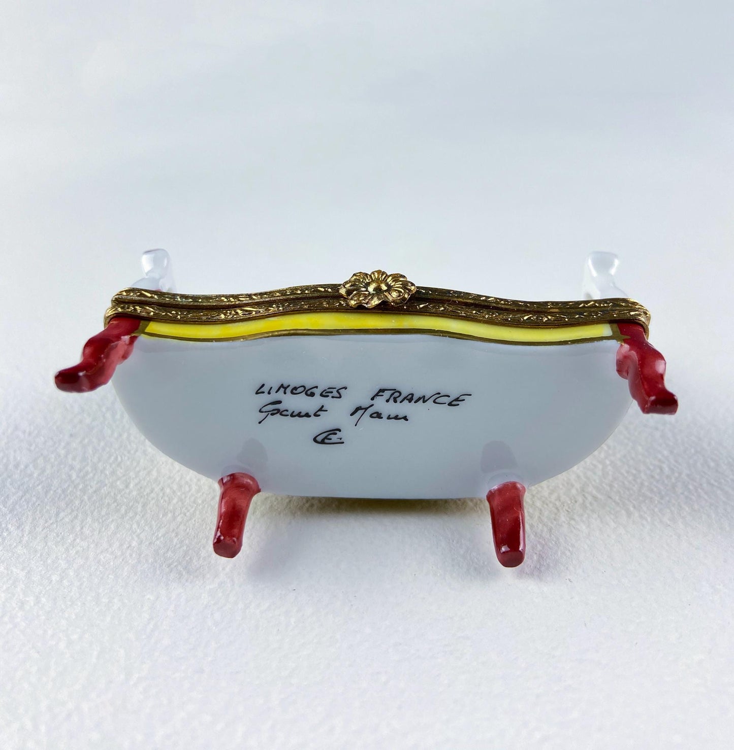 Decorative Limoges France box with gold accents and red feet on a white background