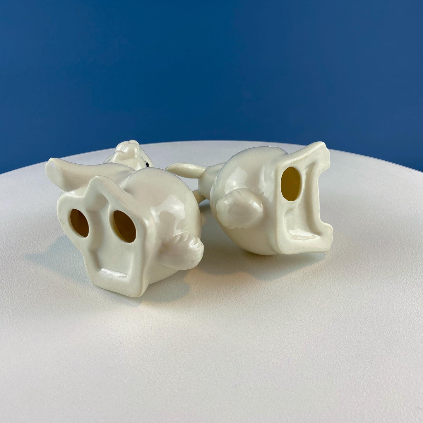 White ceramic bunnies on a white surface with a blue background