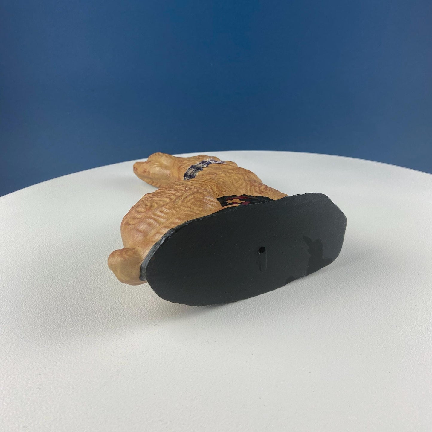 Toy rabbit with a black base on a white surface with a blue background
