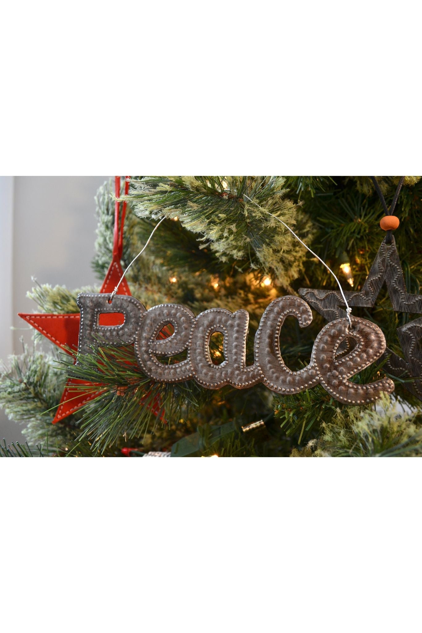 Decorative 'Peace' ornament hanging on a Christmas tree.