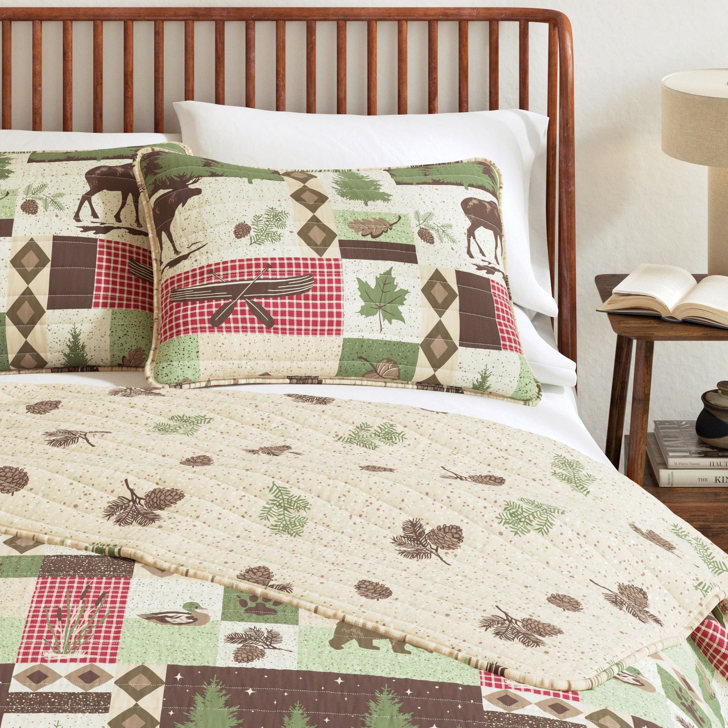 Bedding set with nature-themed design featuring moose, trees, and leaves on a wooden bed.