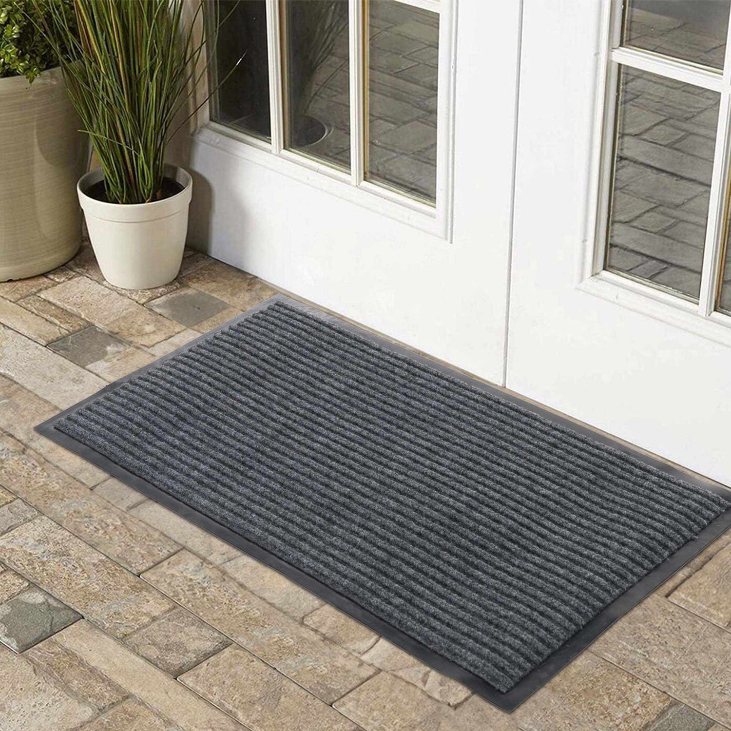Doormats in a cozy entryway featuring a textured gray mat on a stone floor.