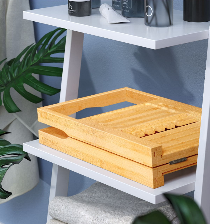 Stylish bamboo Bathtub Caddies on a shelf with toiletries and greenery in a bathroom setting.