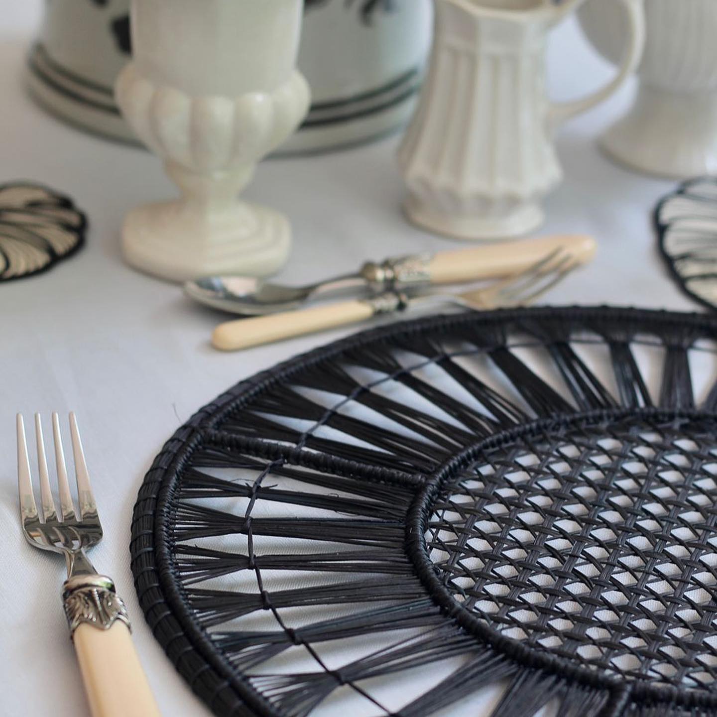 Stylish black Placemats on a dining table with forks and elegant dishware.