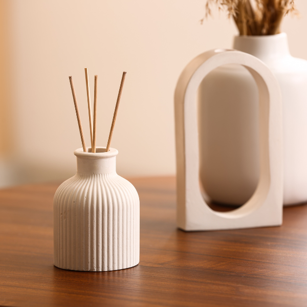 Reed Diffusers in a decorative vase on a wooden table, creating a calming atmosphere.