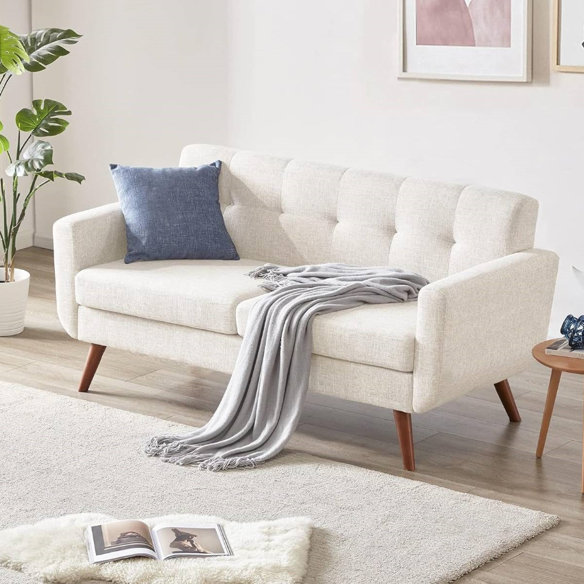 Mid-Century Modern Living Room featuring a stylish light sofa with a blue pillow and a cozy blanket.