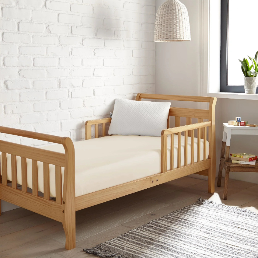 Beautiful wooden toddler bed with a soft mattress, perfect for a child's room featuring cozy decor.