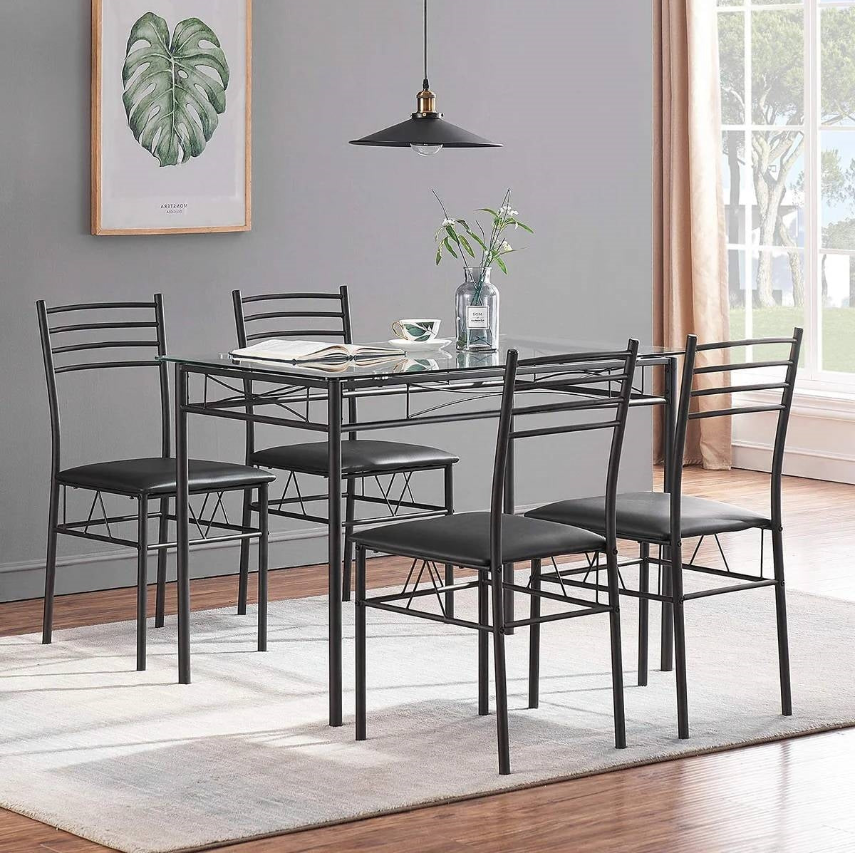A stylish Minimalist Dining Room featuring a glass table and sleek black chairs, enhancing simplicity and elegance.