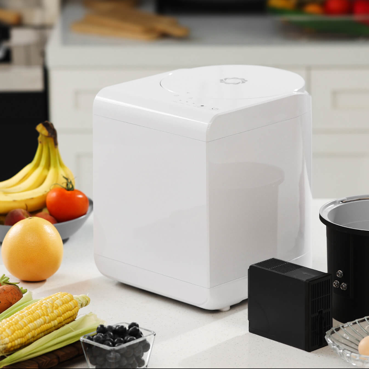 Modern kitchen composter on counter with fresh fruits and vegetables.