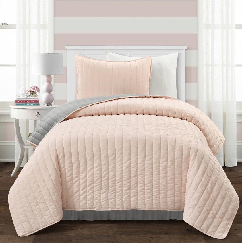 Twin and Twin Xl Quilts and Comforters in soft pink, with matching pillow, on a stylish bed.