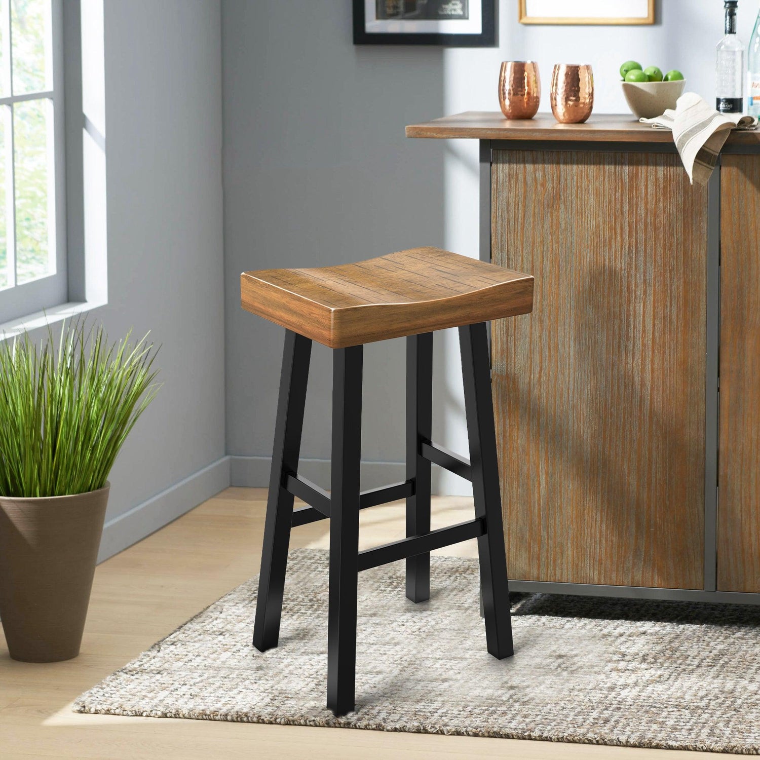 Modern wooden counter stool with black seat, placed beside a round table in a bright room.
