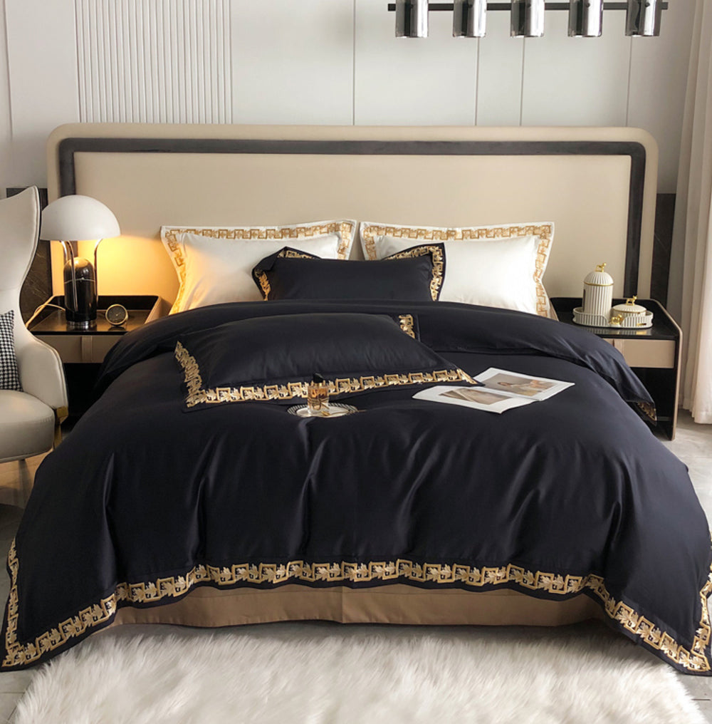 King and California King Duvets in dark navy with ornate gold trim on a plush bed.