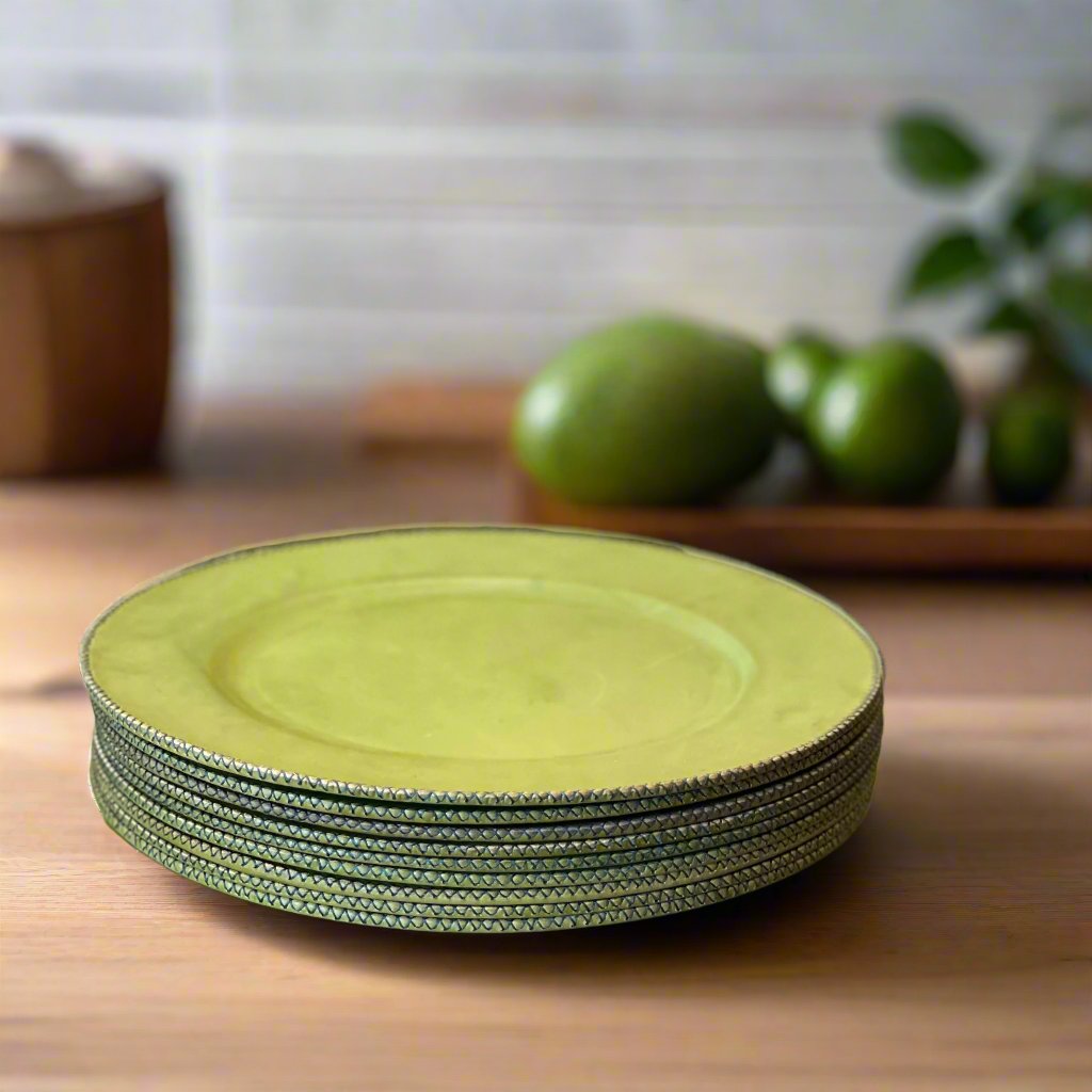 A stack of vibrant green plates on a wooden table with limes in the background, beautifully showcasing the collection of Plates.