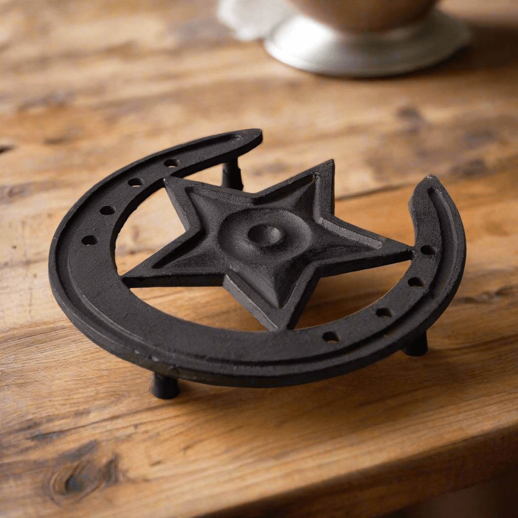 Trivets with a star and moon design made of cast iron on a wooden table.