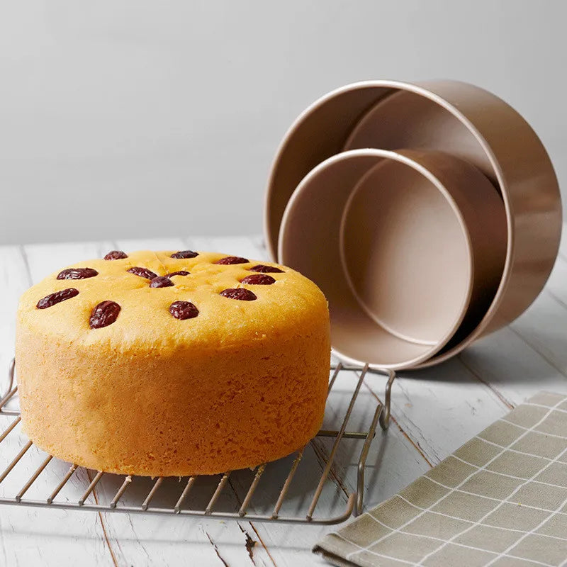 Freshly baked cake next to Bakeware Sets on a wire rack, showcasing quality baking tools.
