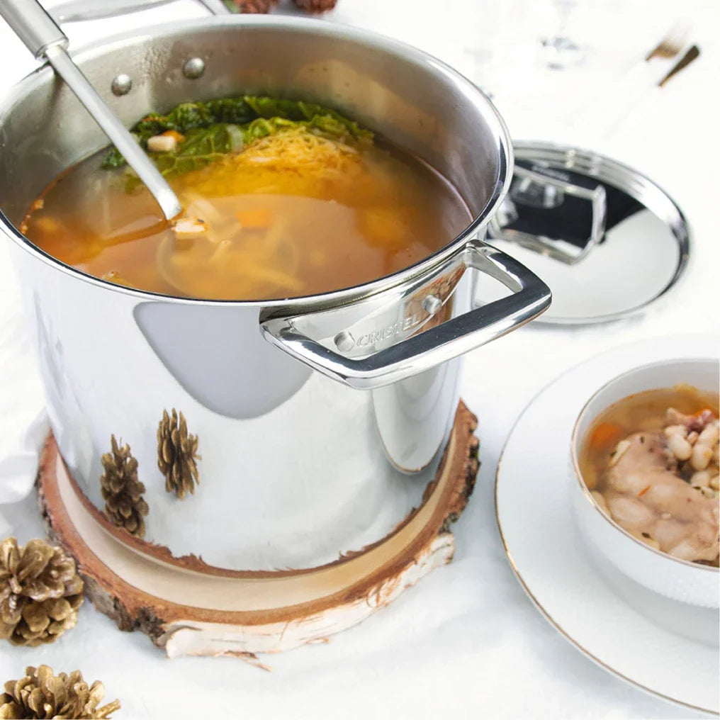 Stainless steel stockpot filled with soup and noodles on a wooden base with pinecones, showcasing versatile stockpots.