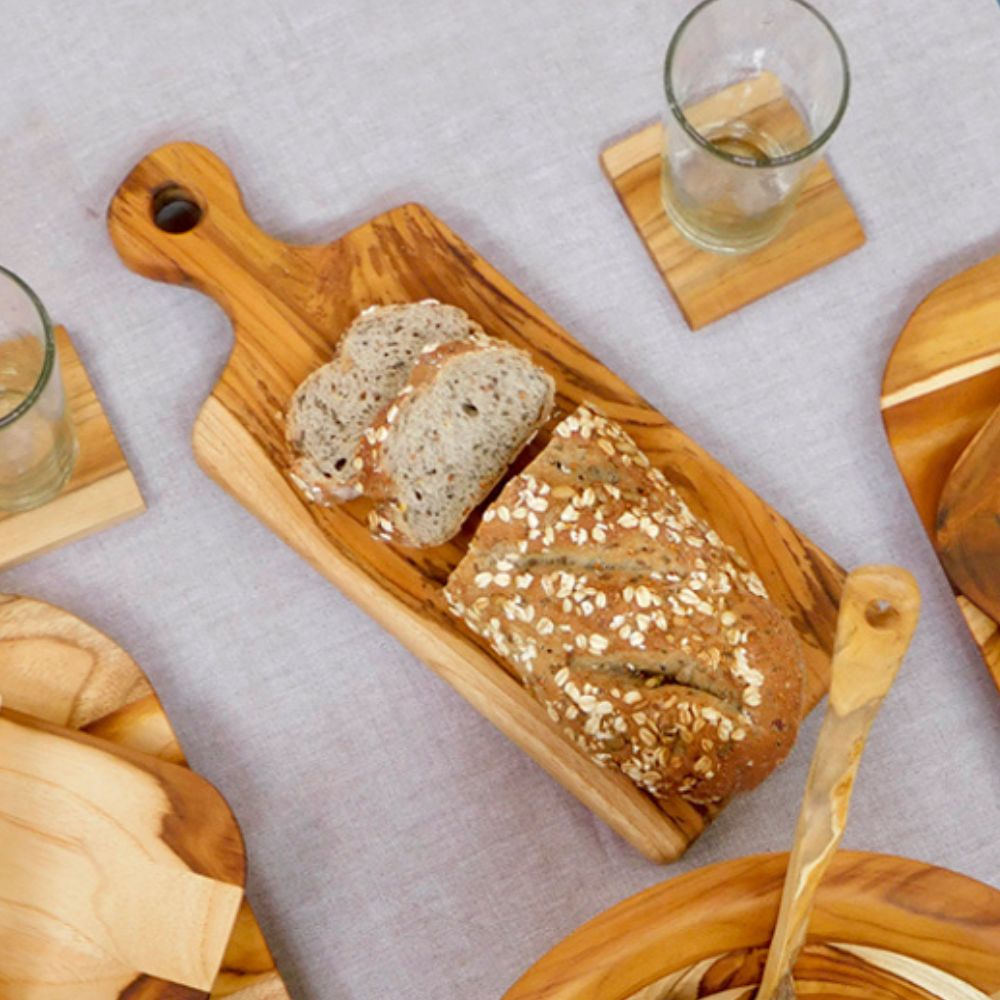 Cutting Boards featuring a wooden board with sliced bread on a table with other wooden items.