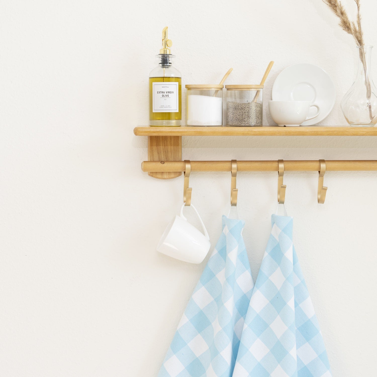 Kitchen Towels hanging in a kitchen, with olive oil, spices, and dishware arranged above.
